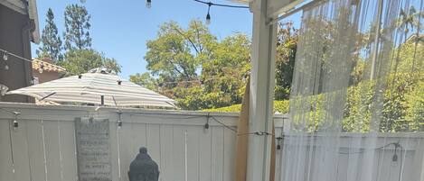 A covered patio area with wicker furniture, a table with a Buddha statue, and a sign with family values.