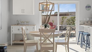 Een lichte keuken met witte kasten, een ronde eettafel en een hanglamp.