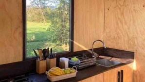 A modern kitchen with wooden cabinets, a built-in stove, and a large window offering a view of greenery.
