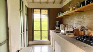 Una cucina stretta con soffitto in legno, una grande finestra e un cestino della spazzatura blu.
