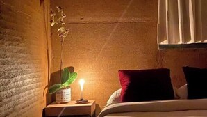 Una camera da letto con un letto, un comodino con una lampada e una finestra con tende.
