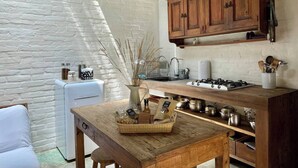 Une cuisine de taille réduite, avec une table en bois rustique, un réfrigérateur blanc et un luminaire suspendu.
