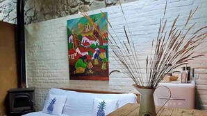 Un salon chaleureux avec un canapé blanc, un tableau au mur et un vase orné de branches décoratives posé sur une table en bois.