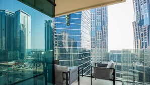 Ein moderner Balkon mit Glasgeländern, zwei grauen Sofas und einem kleinen Tisch.