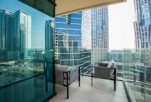 A modern balcony with glass railings, two grey sofas, and a small table.