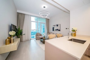 A modern living room with a sofa, coffee table, and a view of a cityscape through large windows.