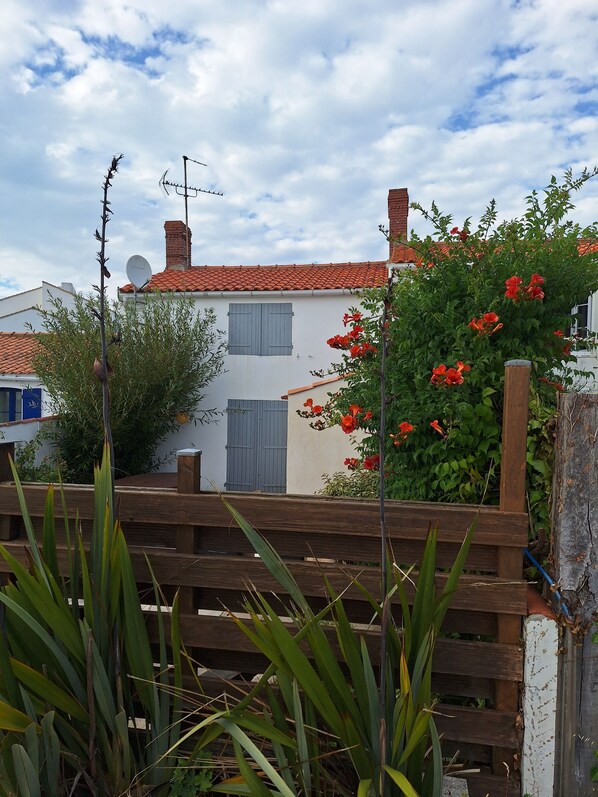 A white building with a red-tiled roof, a satellite dish, and a wooden fence. - Maison Noirmoutrine behind the harbor at l'Herbaudière; pets allowed (Noirmoutier)