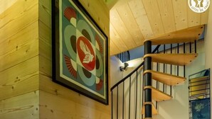 A wooden interior with a staircase, a large woven basket, and a framed artwork on the wall. - CASSANOS - CHANAZ - Gîte (CHANAZ)