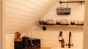 A compact kitchen with a stove, oven, sink, and wooden countertop. - Stunning Tiny House w/ Outdoor Tub & Views (Pontsticill)