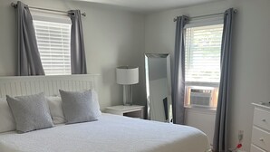 Ein Schlafzimmer mit einem großen Bett, einem Nachttisch mit Lampe, einem Spiegel und einer Kommode.