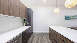 Una cocina moderna con armarios de madera, encimeras de mármol blanco y piso de madera.