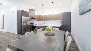 Una cocina moderna con armarios de madera oscura, electrodomésticos de acero inoxidable e iluminación colgante.