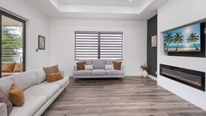 Una sala de estar moderna con un sofá gris, una chimenea y un ventanal con persianas.