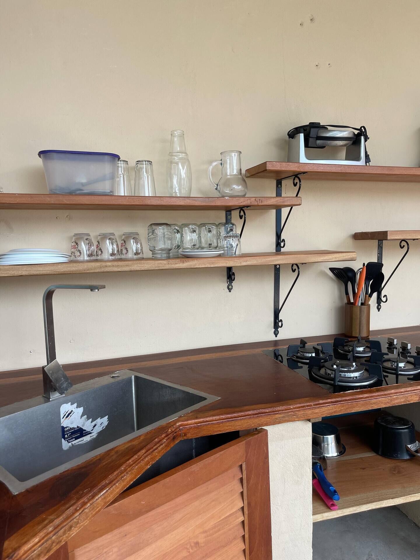 A kitchen with a wooden countertop, a sink, and various kitchen utensils and appliances.