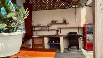 A compact kitchen with wooden countertops, a coffee machine, and a refrigerator.