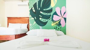 A hotel room with two beds, one wooden and one metal frame, and a large tropical-themed wall mural. - Quadruple Room with View (Moyogalpa)