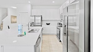 A modern kitchen with white cabinetry, stainless steel appliances, and a white countertop.