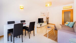 Een moderne woonkamer met een eethoek, een bank, een televisie en een houten deur.