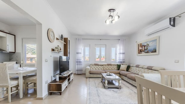 Een moderne woonkamer met een bank, televisie en eethoek.