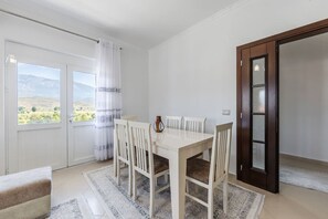 Un espace repas comprenant une table et des chaises, une vue sur l’extérieur et une porte dotée d’un panneau en verre.