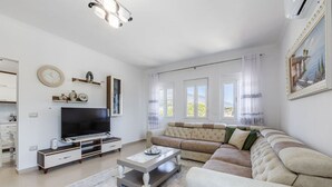 Een moderne woonkamer met een flatscreen televisie, een beige bank en een salontafel.