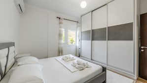 Een slaapkamer met een bed, een kledingkast en een raam met gordijnen.