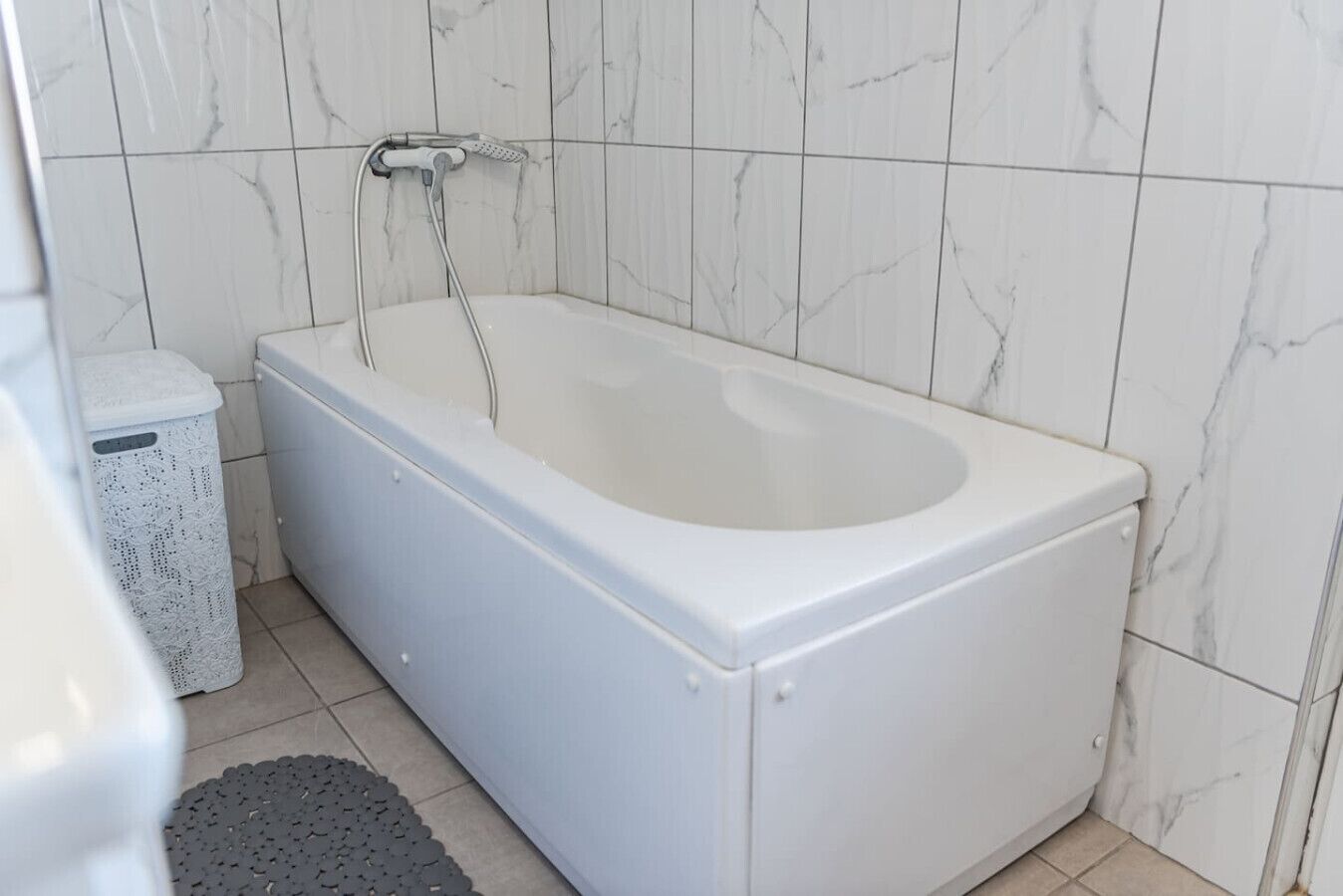 Un baño con una bañera blanca, un inodoro blanco y un cubo de basura blanco.