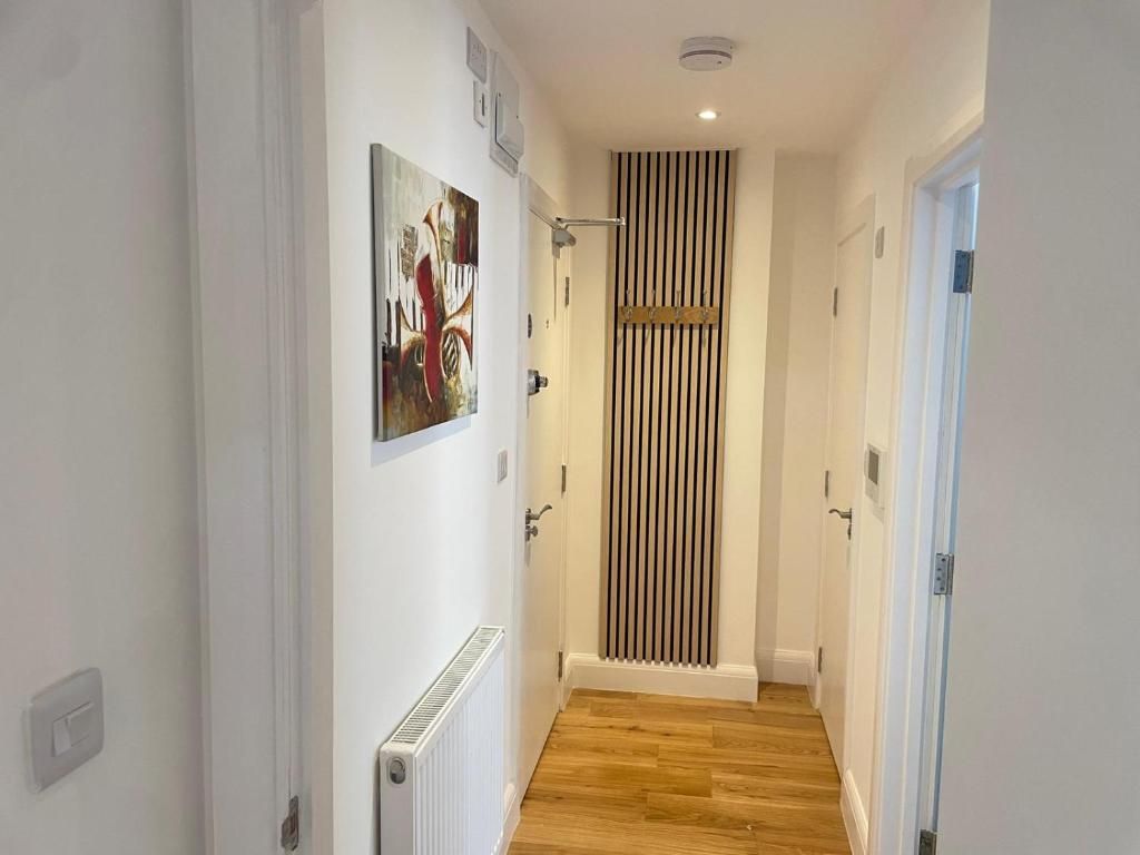 Un couloir avec un radiateur, une porte et un motif de lambris verticaux sur le mur.