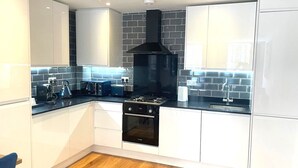 Een moderne keuken met witte kastjes, een zwarte afzuigkap en een betegelde achterwand.