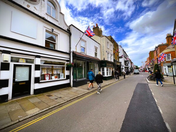 A street with shops, including a bookshop with a window display and a pub with flags.
