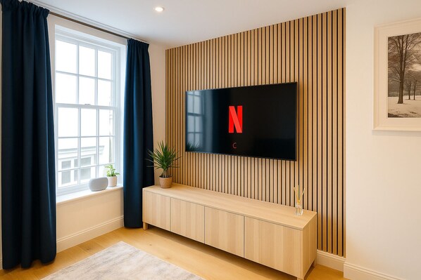 Un salon moderne avec un téléviseur à écran plat fixé sur un mur en bois, une fenêtre avec des rideaux, un banc en bois et un tableau encadré accroché au mur.