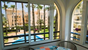 A hotel room with a view of a swimming pool and palm trees. - Anacasa Royal Playa les Marines AP1213 (Denia)