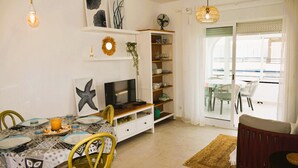 A dining area with a table set for two, a television, and a bookshelf. - Anacasa Royal Playa les Marines AP1213 (Denia)