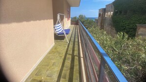A balcony with a swing chair, a view of the sea, and a stone wall.