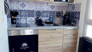 Eine kleine Küche mit Holzausstattung, einer eingebauten Mikrowelle und einem schwarzen Kühlschrank.