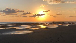 A beach at sunset with footprints in the sand.