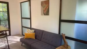 A modern living room with a gray sofa, a yellow pillow, and a wooden side table.