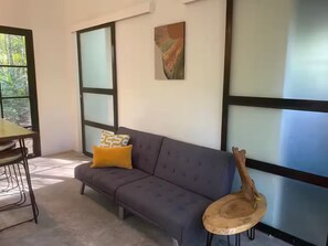 Ein modernes Wohnzimmer mit einem grauen Sofa, einem gelben Kissen und einem Holztisch.