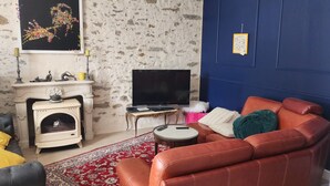 A living room with a fireplace, a sofa, a television, and a patterned rug.