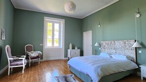 A bedroom with a large bed, a chair, a nightstand, and a dresser.