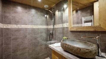 Une salle de bain moderne avec un lavabo en pierre, un meuble-lavabo en bois et un grand miroir.