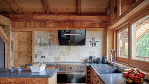 Una cocina moderna con paredes de madera, salpicadero de azulejos, electrodomésticos de acero inoxidable y un ventanal que proporciona luz natural.