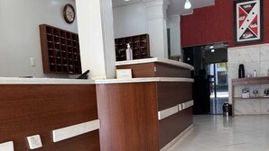 A reception area with a wooden reception desk, a clock on the wall, and a tiled floor.