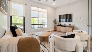 Una sala de estar moderna con un sofá, sillones, una mesa de centro y un televisor montado en la pared.
