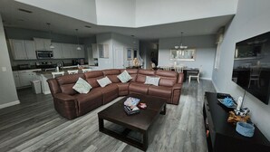 Ein geräumiges Wohnzimmer mit einer braunen Ledersofa-Ecke, einem Couchtisch und einem Essbereich im Hintergrund.