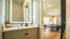 A modern bathroom with a large mirror, a sink, and a vanity with drawers. - DT Designer Gem |  FirePit, Pool Table, Telescope (Fort Worth)