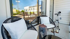 A balcony with wicker chairs, a small table with a candle holder, and a telescope. - DT Designer Gem |  FirePit, Pool Table, Telescope (Fort Worth)