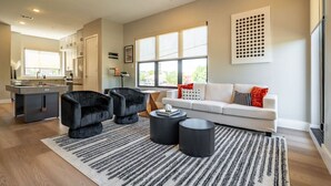 A modern living room with a sofa, two armchairs, a coffee table, and a kitchen area with a dining table. - DT Designer Gem |  FirePit, Pool Table, Telescope (Fort Worth)