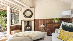 A cozy living room with a fireplace, a sofa, a coffee table, and a view of the outdoors. - The Hut Rawsons in Levens (Kendal)