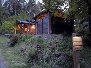 Une cabane rustique avec une façade en bois, une véranda et une enseigne indiquant l’adresse.
